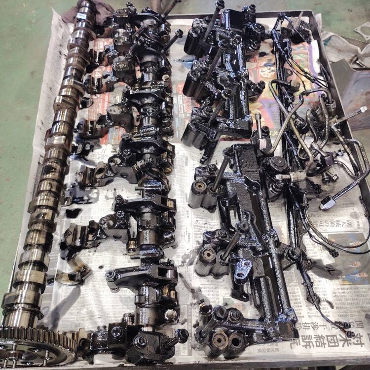 大型トラックのエンジンヘッド分解作業で取り外したカムシャフトや関連部品